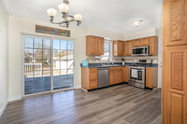 kitchen featuring wood finished floors, visible vents, decorative backsplash, appliances with stainless steel finishes, and dark countertops