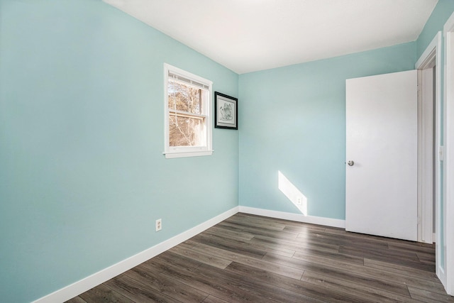 empty room with dark wood-style floors and baseboards