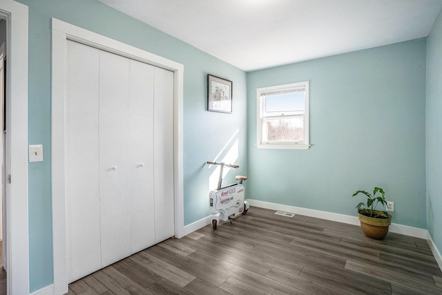 bedroom with visible vents, wood finished floors, a closet, and baseboards