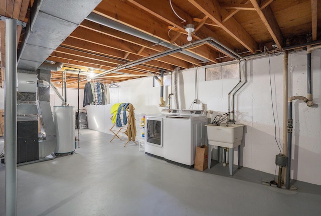 below grade area featuring a sink, heating unit, independent washer and dryer, and water heater