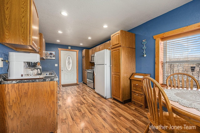 kitchen featuring light wood-style flooring, recessed lighting, appliances with stainless steel finishes, a textured ceiling, and brown cabinets