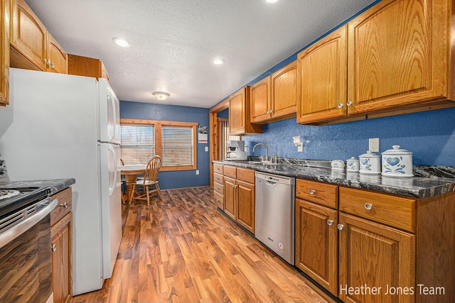 kitchen featuring a sink, appliances with stainless steel finishes, light wood-style flooring, and brown cabinetry