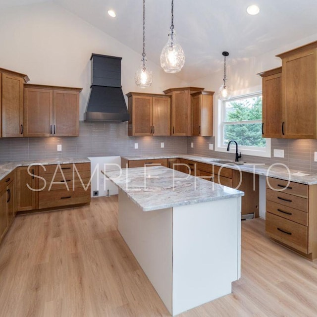 kitchen with light stone counters, brown cabinetry, a sink, custom range hood, and light wood-type flooring