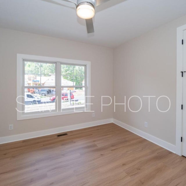 empty room featuring a ceiling fan, light wood-style floors, visible vents, and baseboards