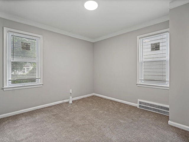 carpeted empty room with baseboards, visible vents, and ornamental molding