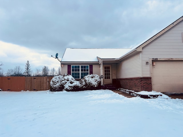 view of front of property featuring brick siding, an attached garage, and fence