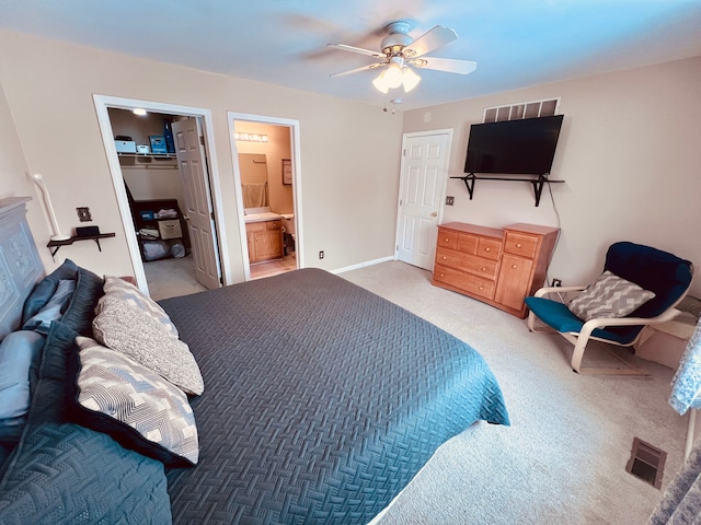 bedroom with visible vents, a walk in closet, ensuite bath, a closet, and light colored carpet