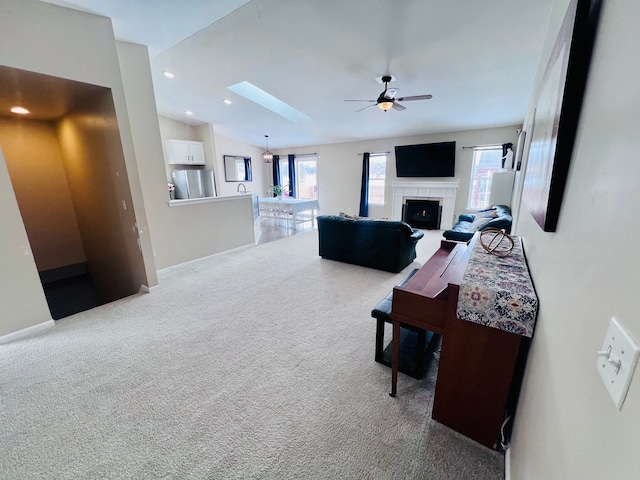 carpeted living room featuring a wealth of natural light, a ceiling fan, a fireplace, and vaulted ceiling