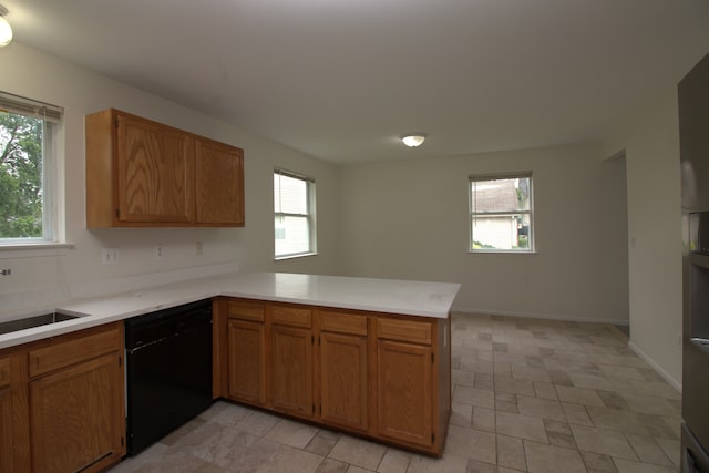 kitchen with a healthy amount of sunlight, a peninsula, a sink, light countertops, and black dishwasher