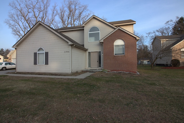 back of property with a lawn and brick siding