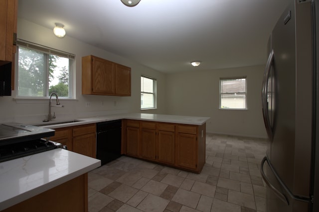 kitchen featuring a sink, freestanding refrigerator, a peninsula, light countertops, and dishwasher