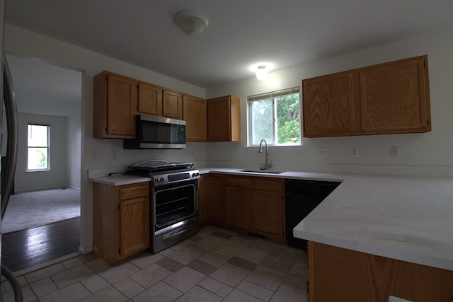 kitchen with a sink, light countertops, brown cabinetry, and stainless steel appliances