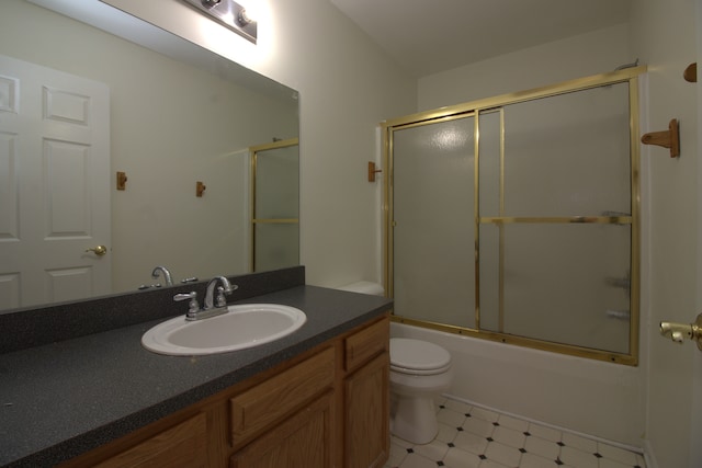 full bath featuring tile patterned floors, combined bath / shower with glass door, toilet, and vanity