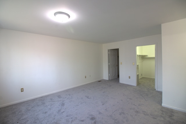 unfurnished bedroom with baseboards, carpet floors, a closet, and a spacious closet