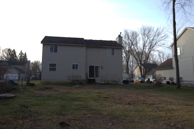 back of house with a yard and a chimney