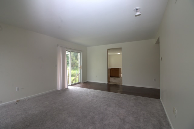 unfurnished room featuring dark colored carpet and baseboards