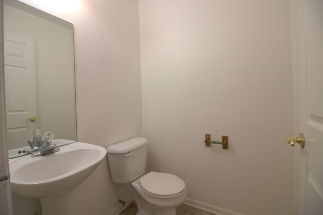 bathroom featuring toilet, baseboards, and a sink