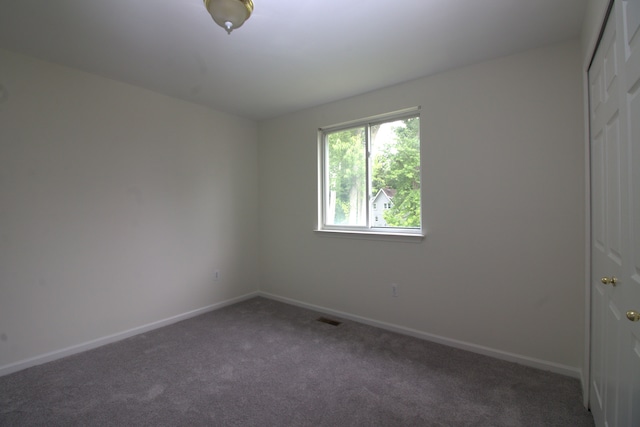 carpeted spare room featuring visible vents and baseboards