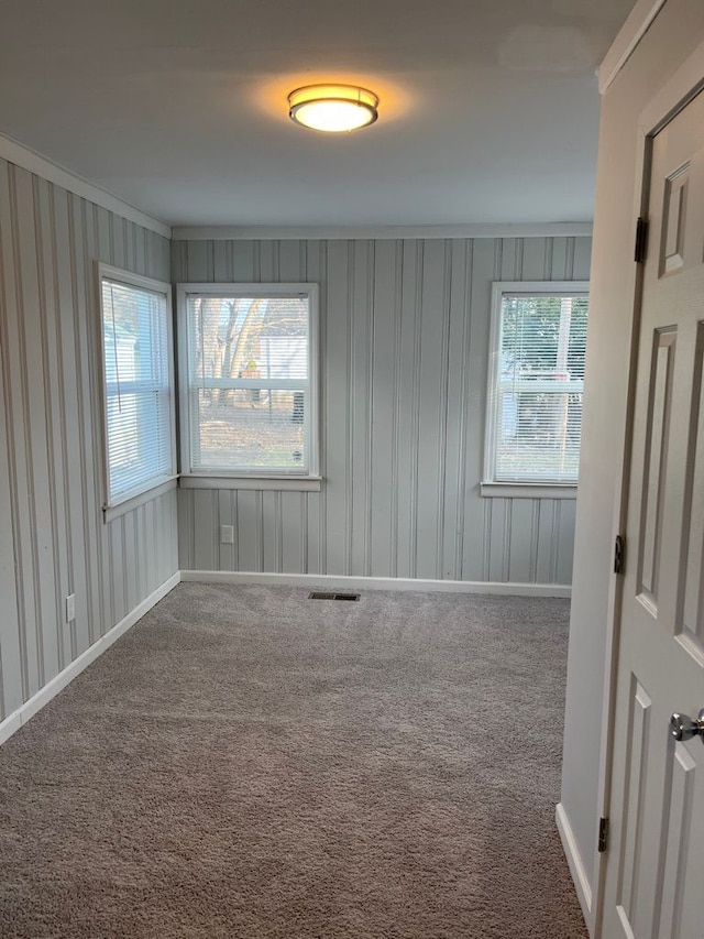 carpeted spare room featuring visible vents and baseboards