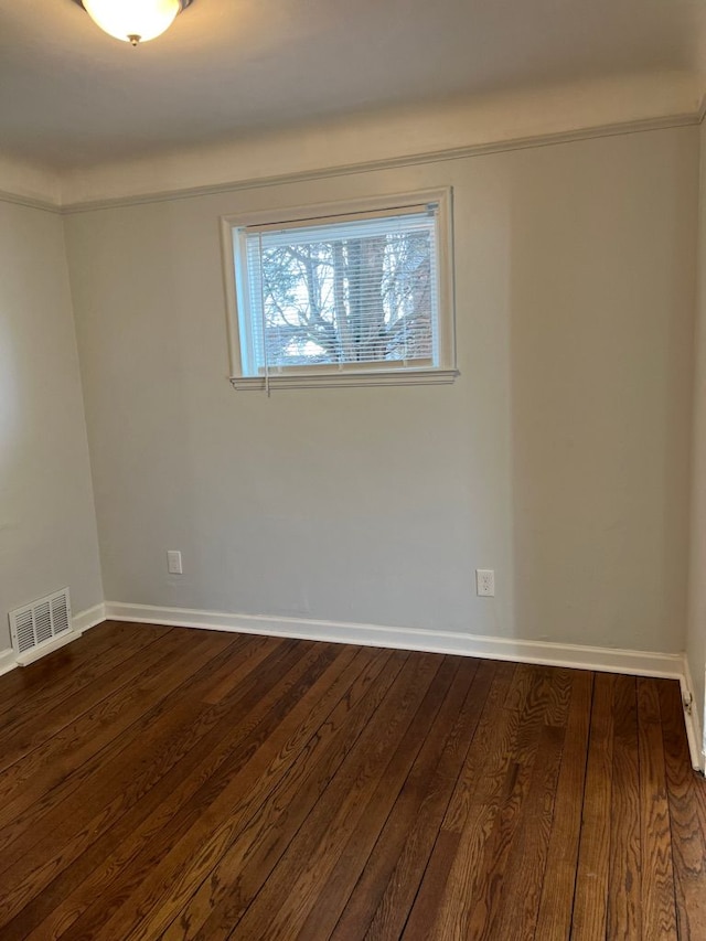 spare room with visible vents, baseboards, and dark wood-style flooring