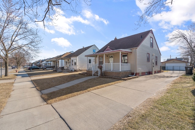 bungalow with a detached garage, a residential view, a porch, an outbuilding, and driveway