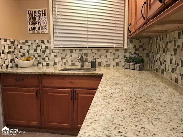 kitchen featuring a sink, decorative backsplash, and light stone countertops