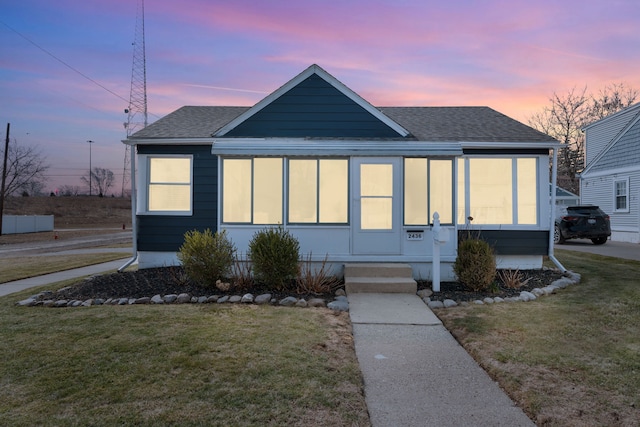 view of front of home featuring a front lawn and a shingled roof