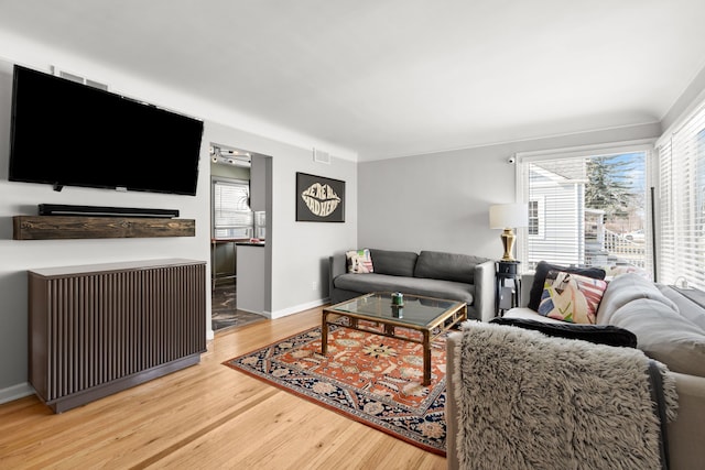 living room featuring visible vents, a healthy amount of sunlight, baseboards, and wood finished floors