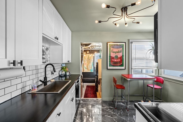 kitchen with dark countertops, marble finish floor, a wealth of natural light, and a sink