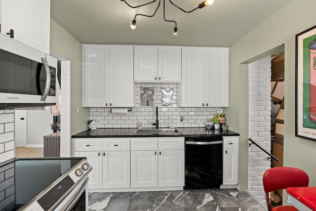 kitchen with dark countertops, backsplash, appliances with stainless steel finishes, and a sink