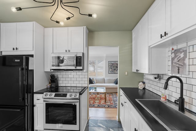 kitchen featuring a sink, tasteful backsplash, dark countertops, white cabinetry, and stainless steel appliances