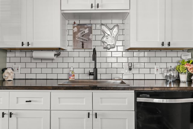 kitchen featuring dark countertops, white cabinets, dishwashing machine, and a sink