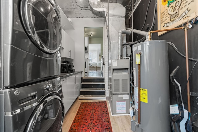 laundry area with water heater, stacked washer and clothes dryer, and light wood-type flooring