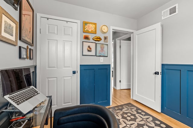 interior space featuring visible vents, wainscoting, and light wood finished floors