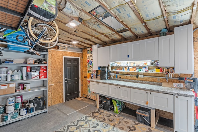 kitchen with light stone countertops, unfinished concrete floors, and white cabinetry