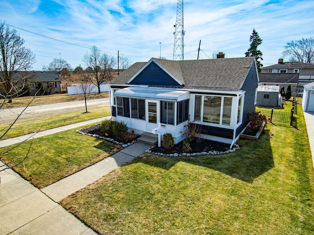 bungalow-style house featuring fence, roof with shingles, a front lawn, and a sunroom