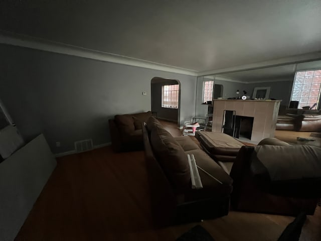 living room with plenty of natural light, visible vents, arched walkways, and a tile fireplace