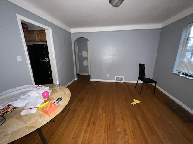 bedroom featuring visible vents, wood finished floors, freestanding refrigerator, arched walkways, and baseboards