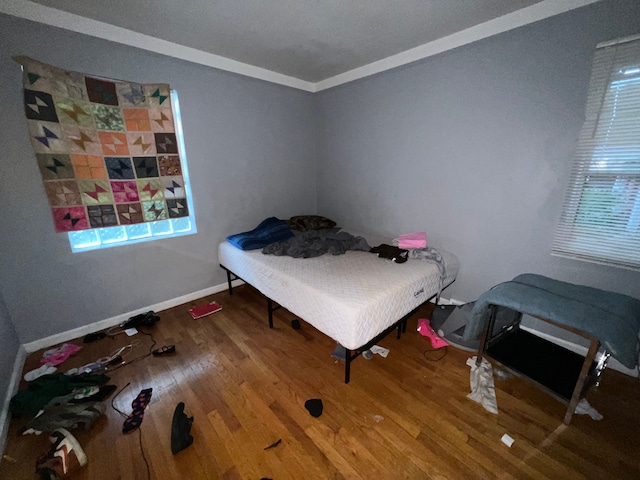 bedroom featuring baseboards, wood finished floors, and crown molding