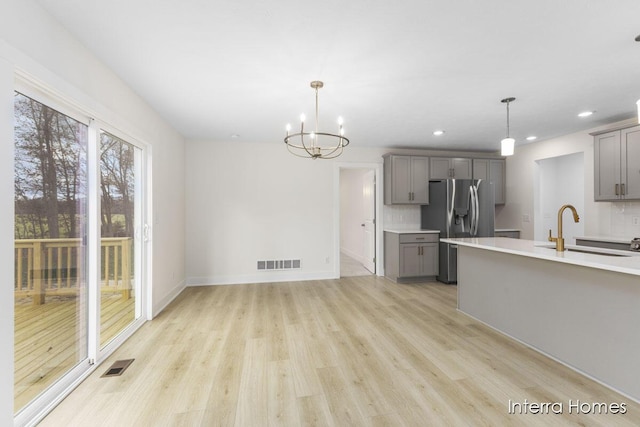 kitchen with visible vents, gray cabinets, a sink, stainless steel fridge, and light countertops