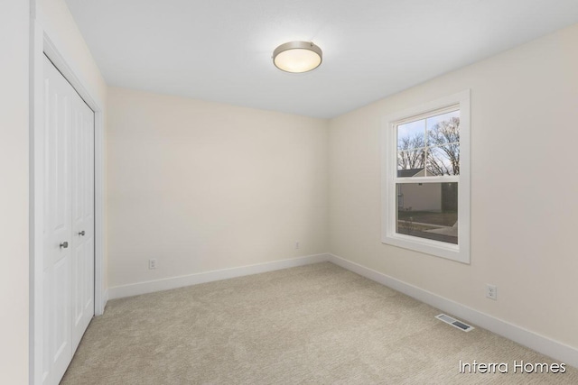 unfurnished bedroom featuring carpet, visible vents, a closet, and baseboards