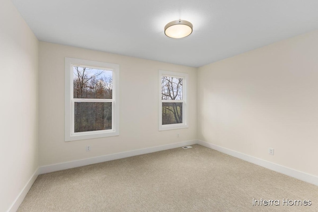 empty room with visible vents, light colored carpet, and baseboards