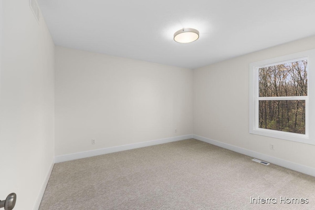 carpeted spare room with visible vents and baseboards