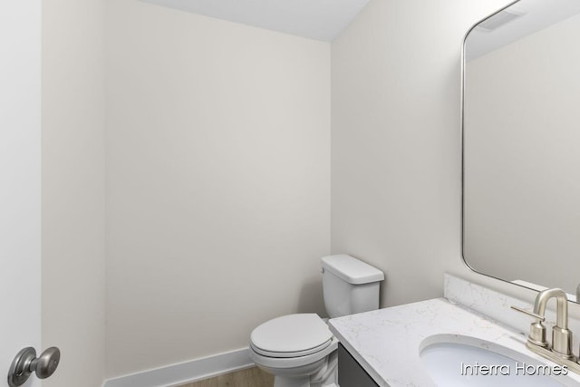 bathroom featuring visible vents, baseboards, toilet, wood finished floors, and vanity