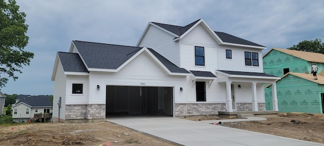 1442 Kimber Dr Unit 120, Lowell, MI 49331 - modern farmhouse style home featuring stone siding, concrete driveway, covered porch, roof with shingles, and a garage