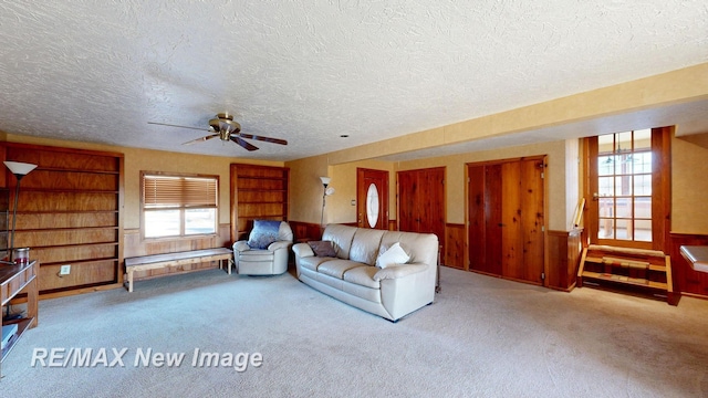 unfurnished living room with wooden walls, a wainscoted wall, a textured ceiling, and carpet