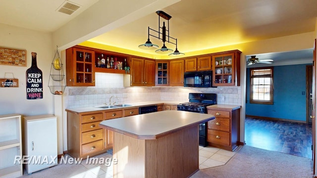 kitchen with visible vents, a kitchen island, light countertops, black appliances, and a sink