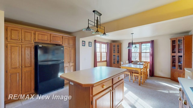 kitchen featuring a kitchen island, pendant lighting, light countertops, light carpet, and freestanding refrigerator