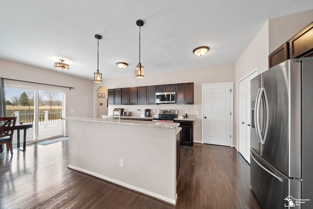 kitchen with pendant lighting, an island with sink, dark wood-style floors, stainless steel appliances, and dark brown cabinets