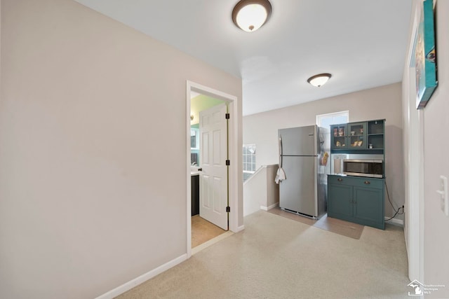 kitchen with light colored carpet, stainless steel appliances, and baseboards